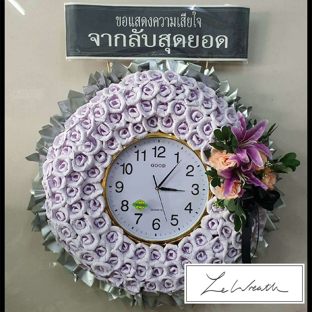 พวงหรีดนาฬิกาตกแต่งด้วยดอกไม้จันทน์ประดิษฐ์สีม่วง ตัดกับพื้นหลังสีเงิน
