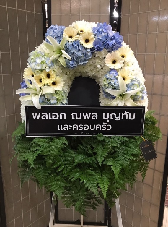 พวงหรีดดอกไม้สด ที่ช่วยเพิ่มสีสันและความสดใสให้แก่ผู้คนในงานด้วยโทนสีฟ้า-ขาว ซึ่งประดับด้วยดอกไฮเดรนเยีย ดอกมัม ลิลลี่ เยอบีร่า และใบนาคราช