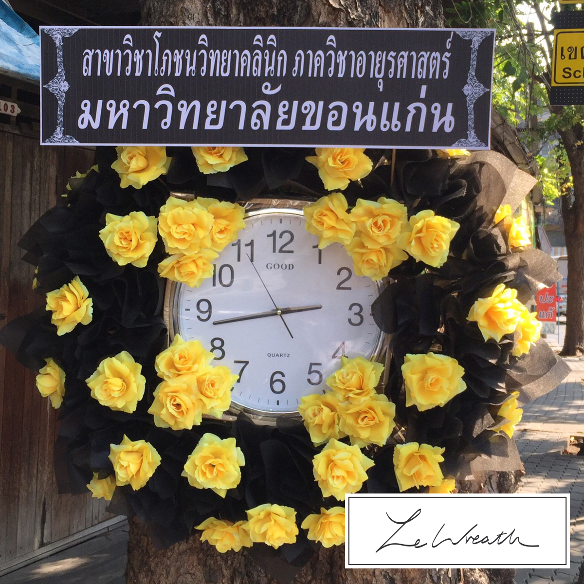 พวงหรีดนาฬิกา ตกแต่งด้วยดอกไม้ประดิษฐ์โทนสีดำ แซมด้วยสีเหลือง ให้ความรู้สึกสุภาพ ผ่อนคลาย